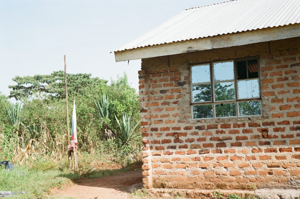 Fotka kostela adventistů sedmého dne. Neomítnutá cihlová budova s plechovou střechou a malými okny, jedno sklo je rozbité.