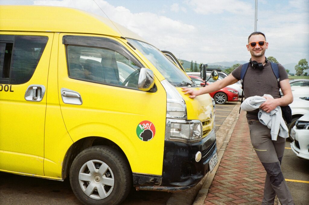 Můj muž stojí vedle malého žlutého školního autobusu s logem projektu Rael.